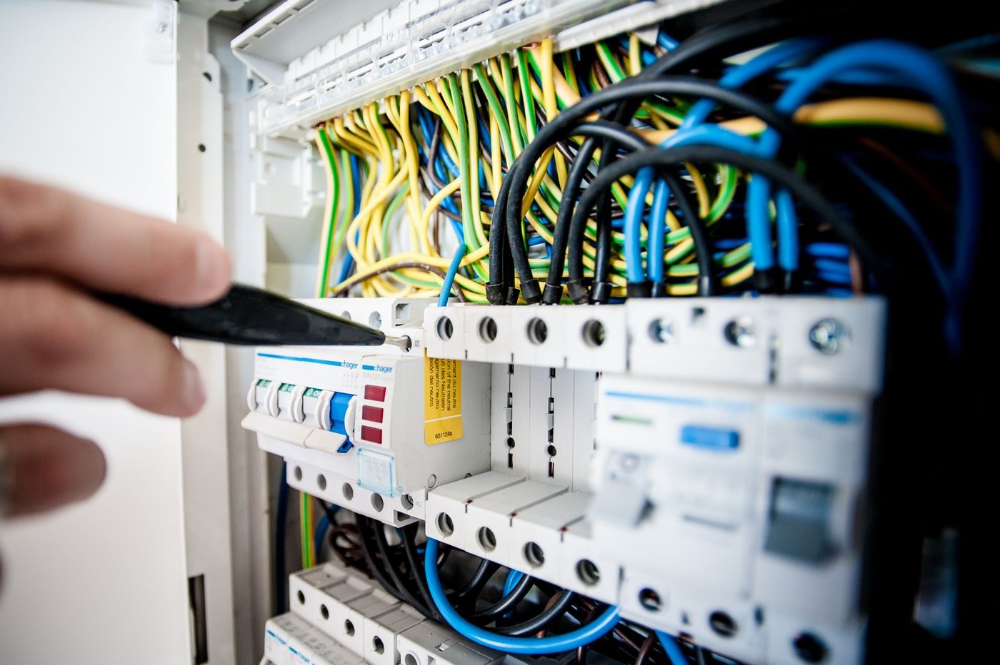 Miniature circuit breakers and RCDs on a DIN rail inside a consumer unit, with brown, blue and green-and-yellow conductors dressed into their terminals